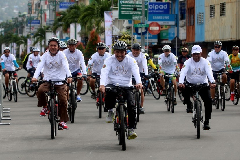 Menko Maritim Luhut B Panjaitan (kedua dari kiri) didampingi Gubernur Maluku Said Assagaff (kiri) bersepeda mengelilingi sejumlah ruas jalan di Kota Ambon usai membuka lomba balap sepeda internasional Tour de Moluccas 2017 di Ambon, Maluku, Minggu (17/8). 