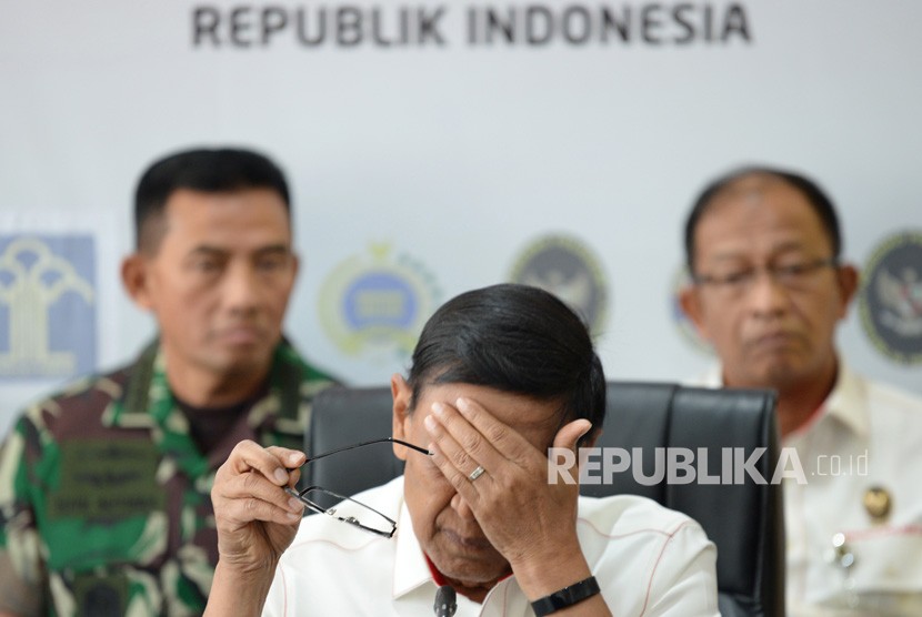 Menko Polhukam Wiranto (tengah) mengusap wajahnya saat memberikan keterangan pers di Kemenko Polhukam, Jakarta, Kamis (26/9/2019).