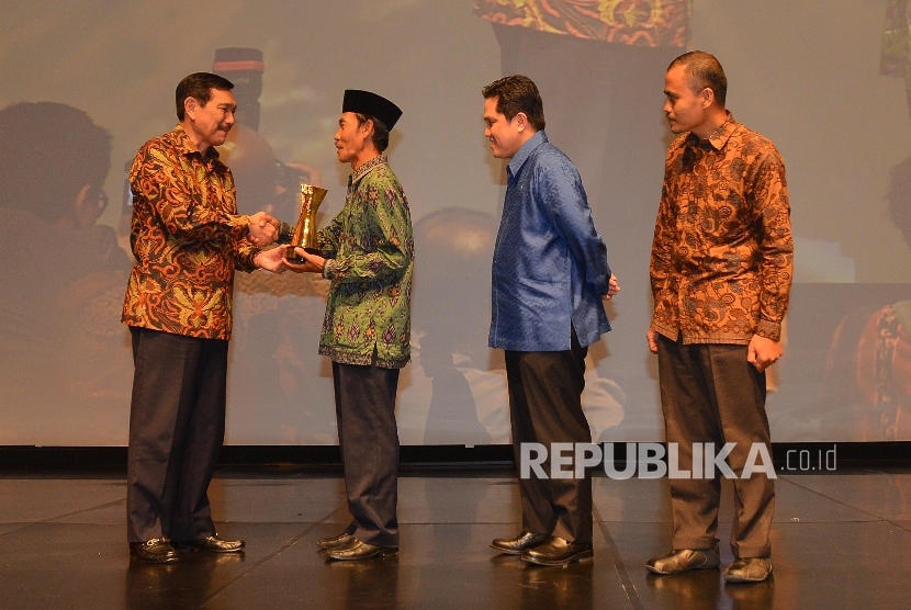 Menkopolhukam Luhut Panjaitan memberikan trophy tokoh perubahan kepada TGH Hasanain saat malam Penganugerahan Tokoh Perubahan Republika 2015 di Jakarta, Senin (21/3) malam. (Republika/Raisan Al Farisi)