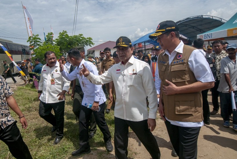 Menko Polhukam Wiranto (kedua kanan) berbincang dengan Kepala BNPB Letjen TNI Doni Monardo (kanan) saat mengunjungi pengungsi korban bencana di kompleks Hunian Sementara (Huntara) Desa Mpanau, Sigi, Sulawesi Tengah, Senin (1/7/2019).