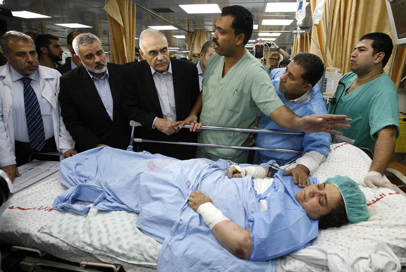  Menlu Mesir Mohamed Kamel Amr (ketiga dari kiri) dan Perdana Menteri Palestina Ismail Haniyeh saat menjenguk seorang wanita Palestina yang terluka dalam serangan udara Israel di sebuah rumah sakit di Gaza, Selasa (20/11). (AP Pool/Ahmed Zakot)