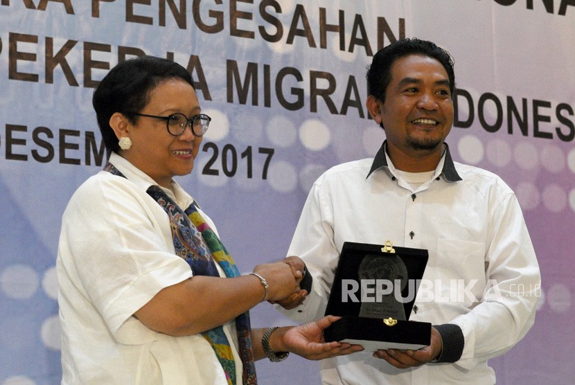 Menlu Retno Marsudi (kiri) menerima penghargaan dari Ketua Umum Serikat Buruh Migran Indonesia (SBMI) Hariyanto (kanan) pada Peringatan Hari Buruh Migran Internasional di Islamic Centre, Bekasi, Jawa Barat, (17/12) malam. 