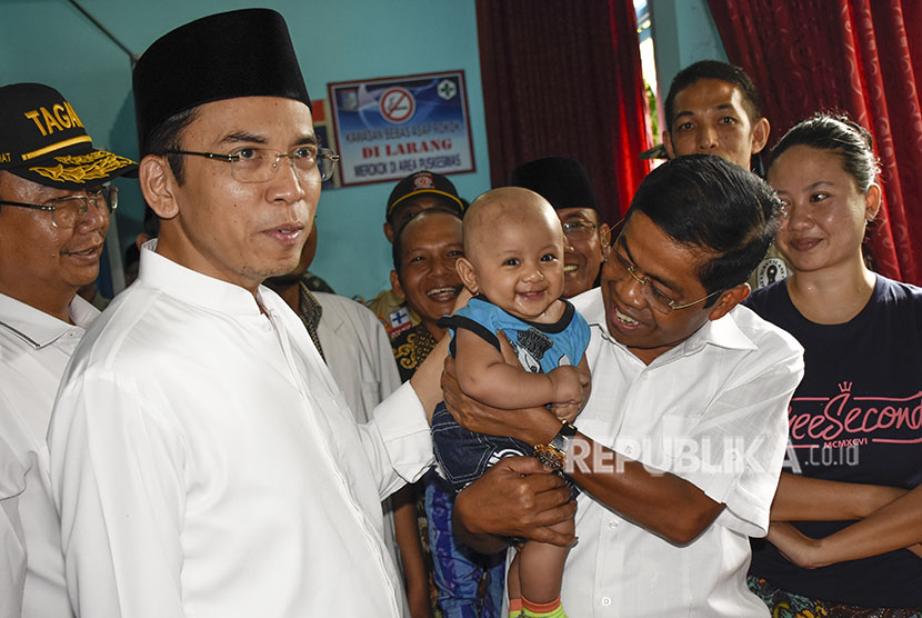 Mensos Idrus Marham (kedua kanan) disaksikan Gubernur NTB TGB Zainul Majdi (kedua kiri) menggendong anak korban tambang emas ilegal yang dirawat di Puskesmas Sekotong, Lombok Barat, NTB, Kamis (21/6).