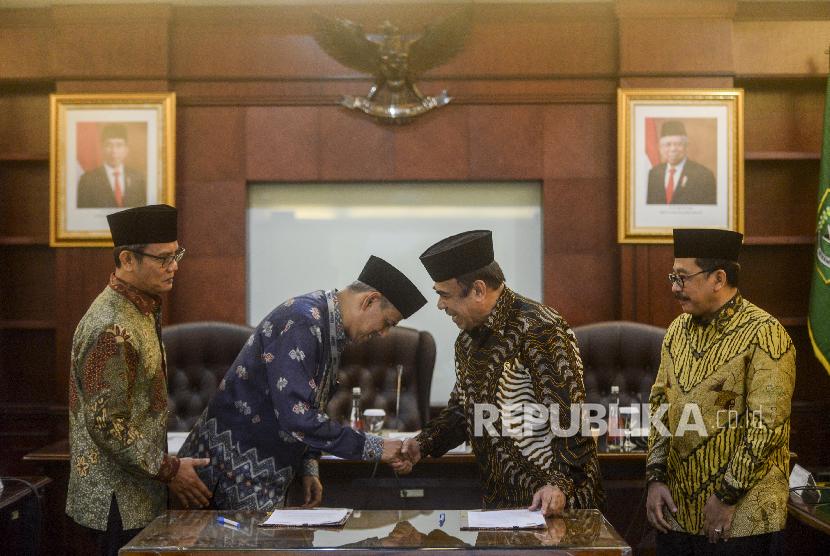 Menteri Agama Fachrul Razi (kedua kanan) bersama Kepala Badan Pengelola Keuangan Haji (BPKH) Anggito Abimanyu (kedua kiri) dan Wakil Menteri Agama Zainut Tauhid (kanan) bersalaman usai penandatanganan nota kesepahaman di Kementerian Agama, Jakarta, Rabu (4/3).