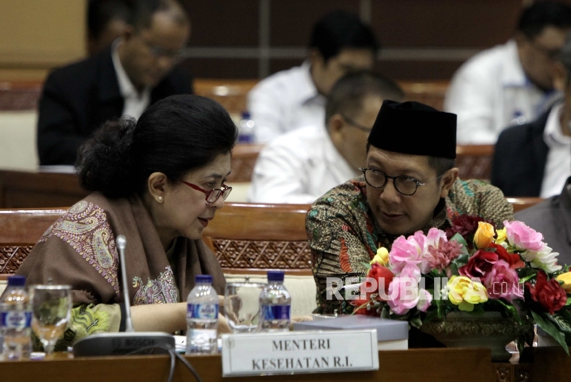 Menteri Agama Lukman Hakim Saifuddin (kanan) berbincang bersama Menteri Kesehatan Nila Farid Moeloek (kiri) disela rapat kerja dengan Komisi VIII DPR RI di Kompleks Parlemen, Jakarta, Senin (16/1).