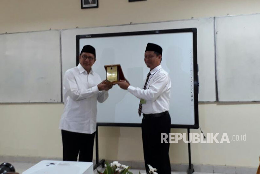 Menteri Agama Lukman Hakim Saifuddin menerima plakat dari Kepala MAN 4 Jakarta Ismail Nur usai meninjau UNBK di MAN 4 Jakarta, Selasa (11/4). 