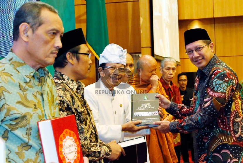 Menteri Agama RI Lukman Hakim Saifudin (kanan) secara simbolis menyerahkan Alquran dengan terjemahan bahasa daerah kepada beberapa perwakilan tokoh lintas agama dan tokoh daerah pada peluncurannya, Kamis (3/12), di Jakarta. 