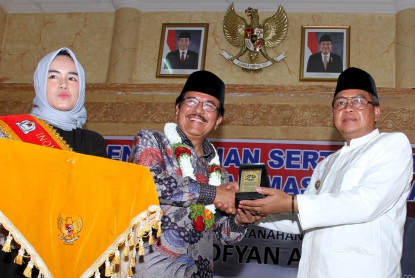 Menteri Agraria dan Tata Ruang/Kepala Badan Pertanahan Nasional Sofyan Djalil (tengah) memberikan cenderamata kepada Bupati Aceh Barat Ramli Ms (kanan) seusai menyerahkan sertifikat tanah wakaf di Aula Kantor Bupati Aceh Barat, Aceh, Jumat (15/2/2019). 