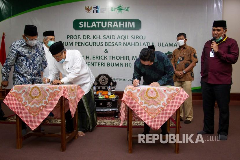 Menteri Badan Usaha Milik Negara (BUMN) Erick Thohir (kedua kanan) bersama Ketua Umum Pengurus Besar Nahdlatul Ulama (PBNU) Said Aqil Siradj (kedua kiri) melakukan penandatanganan nota kesepahaman (MoU) di Pondok Pesantren Luhur Al-Tsaqafah, Jakarta, Jumat (4/9/2020). 
