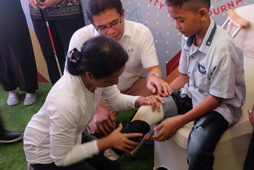 Menteri BUMN RI Rini M. Soemarno didampingi Direktur Utama Telkom Alex J. Sinaga saat memasangkan kaki palsu kepada penyandang disabilitas pada acara Telkom Disability Care  - Charity Golf Tournament di Jakarta (5/8).