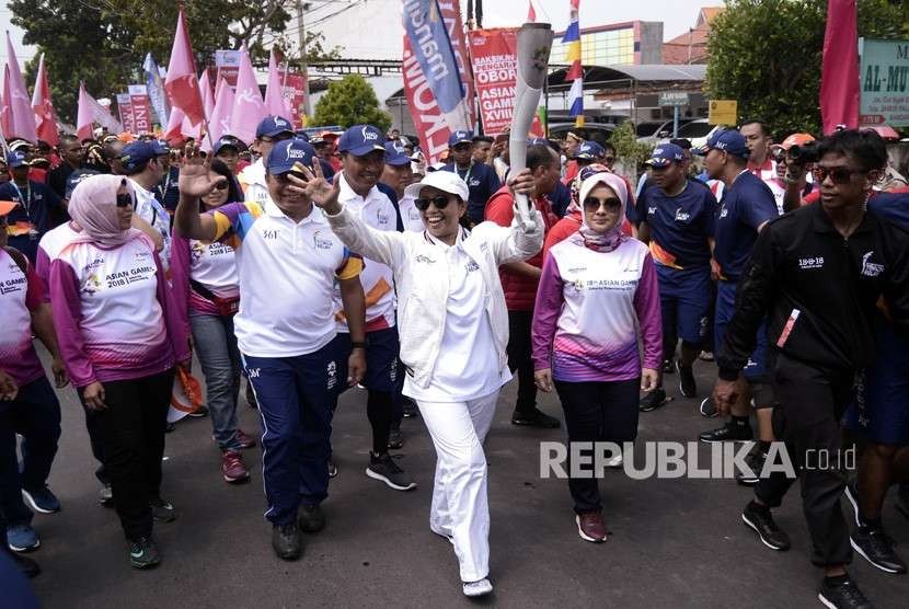 Menteri BUMN Rini M. Soemarno (tengah) membawa obor saat prosesi Torch Relay Asian Games (AG) 2018 melintasi Jalan Cut Nyak Dien Bandar Lampung, Lampung, Rabu (8/8). 