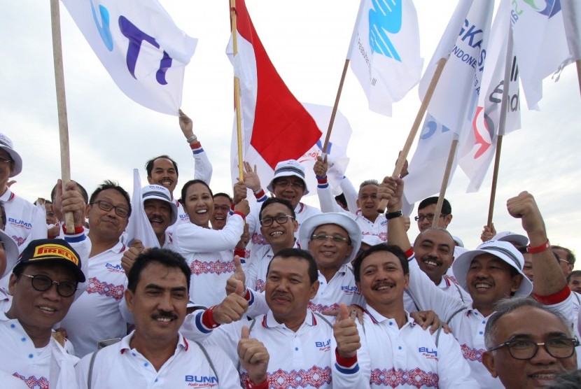 Menteri BUMN Rini Soemarno (tengah) didampingi Direktur Utama Garuda Indonesia Arif Wibowo dan sejumlah direksi BUMN mengibarkan bendera di Bukit Merese Tanjung Aan, Lombok, NTB, Jumat (27/1). 