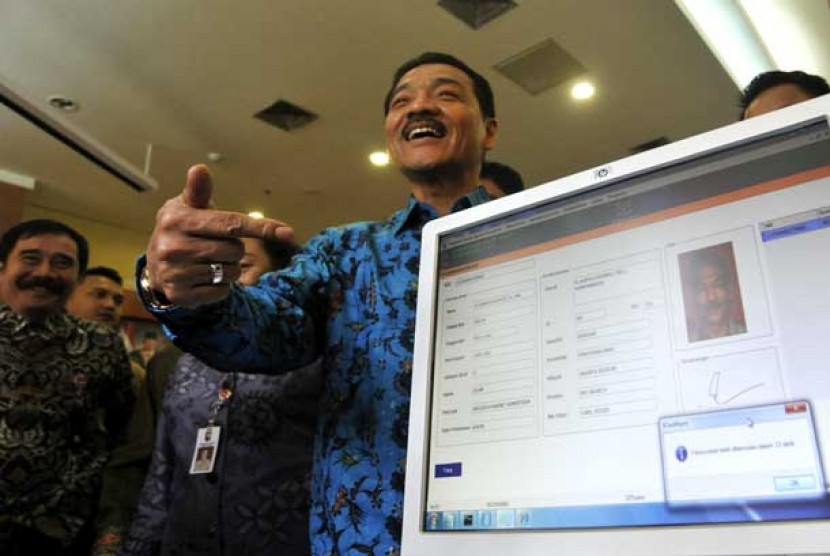 Menteri Dalam Negeri Gamawan Fauzi (tengah) tersenyum seusai memindai data e-KTP miliknya di Kementerian Dalam Negeri, Jakarta Pusat, Kamis (8/11).