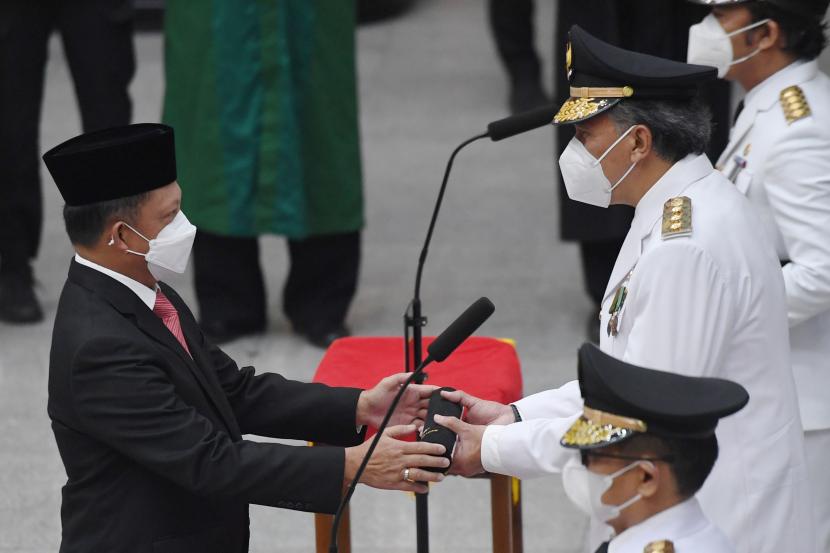 Menteri Dalam Negeri Tito Karnavian (kiri) menyerahkan surat keputusan kepada penjabat Gubernur Bangka Belitung Ridwan Jamaludin (kanan) saat pelantikan lima penjabat gubernur di Kemendagri, Jakarta Pusat, Kamis (12/5/2022).