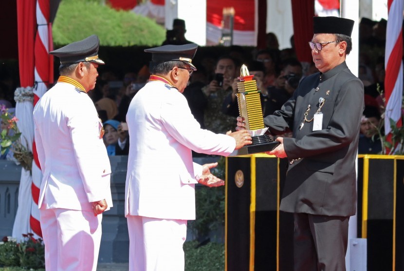 Menteri Dalam Negeri Tjahjo Kumolo (kanan) menyerahkan penghargaan Samkarya Parasamya Purnakarya Nugraha kepada Gubernur Jawa Timur Soekarwo (kedua kanan) saat Upacara Hari Jadi Ke-72 Provinsi Jawa Timur di Tugu Pahlawan, Surabaya, Jawa Timur, Kamis (12/10). 