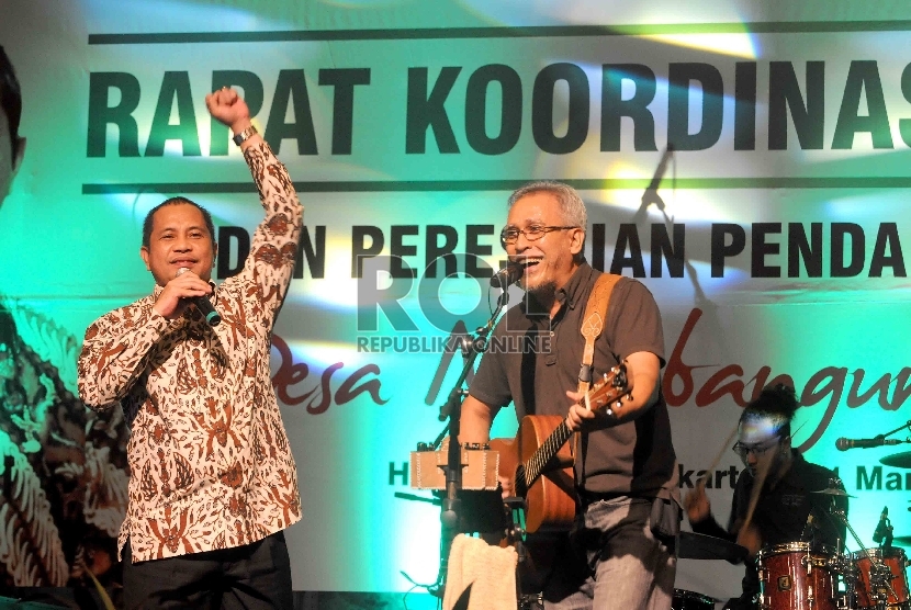 Menteri Desa, Pembangunan Daerah Tertinggal dan Transmigrasi (PDTT) Marwan Jafar bersama Musisi, Iwan Fals bernyanyi saat pembukaan Rapat Koordinasi Nasional Kementerian Desa PDTT di Jakarta, Selasa (31/3).