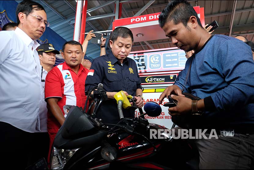 Menteri ESDM Ignasius Jonan (ketiga kiri) didampingi Direktur Pemasaran Retail PT Pertamina Mas'ud Khamid (kiri) mengisi bahan bakar minyak (BBM) ke tangki sepeda motor konsumen pada peresmian BBM satu harga, di SPBU Kompak, Nias Utara, Sumatera Utara, Kamis (6/12)