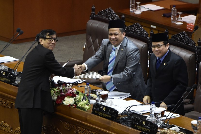 Menteri Hukum dan HAM Yasonna Laoly (kiri) menyerahkan salinan pandangan akhir pemerintah kepada pimpinan rapat paripurna Fahri Hamzah (tengah) dan Taufik Kurniawan (kanan) terkait RUU Jasa Konstruksi di Kompleks Parlemen Senayan, Jakarta, Kamis (15/12). 