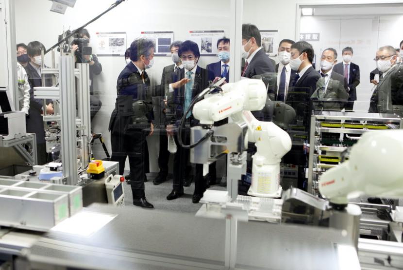 Menteri Kesehatan Jepang Norihisa Tamura menyaksikan demonstrasi prototipe mesin penguji Covid-19 otomatis yang menggunakan lengan robot. 