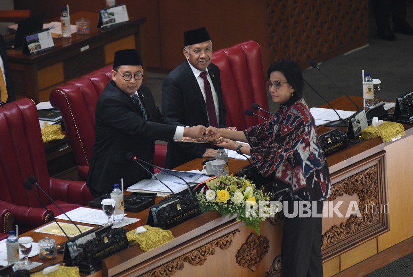 Menteri Keuangan Sri Mulyani Indrawati (kanan) memberikan draft tanggapan pemerintah kepada Ketua Rapat Paripurna Fadli Zon (kiri) didampingi Wakil Ketua DPR Agus Hermanto (tengah) pada Rapat Paripurna DPR di Kompleks Parlemen, Senayan, Jakarta, Selasa (11/6/2019).