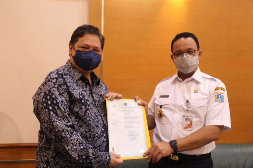 Menteri Koordinator Bidang Perekonomian yang juga Ketua Umum DPP Partai Golkar Airlangga Hartarto (kiri) menyerahkan sertifikat Yellow Clinic vaksinasi Partai Golkar kepada Gubernur DKI Jakarta Anies Baswedan (kanan) di Balai Kota DKI Jakarta, Kamis (19/8).