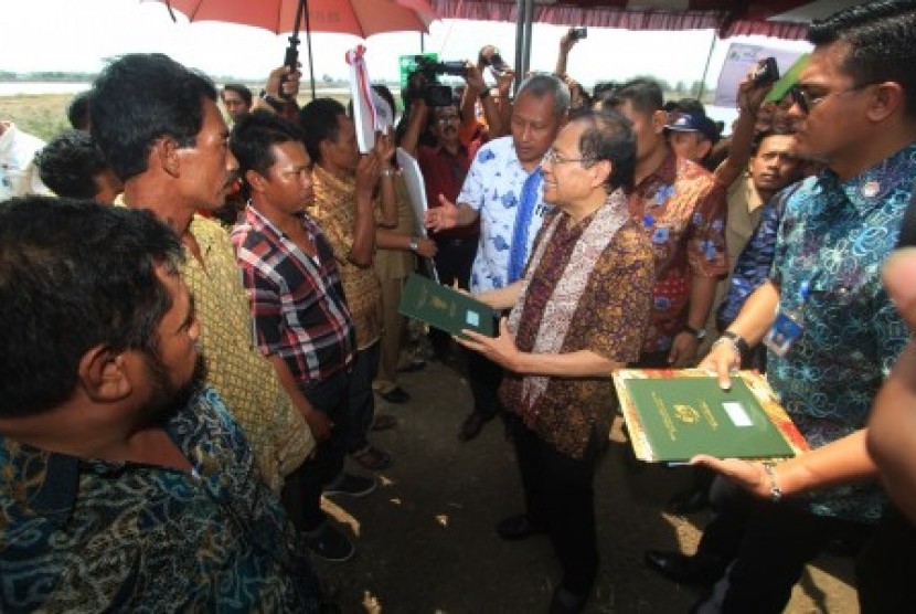 Menteri Koordinator Kemaritiman & Sumber Daya Rizal Ramli (tengah) memberikan kartu BPJS secara simbolis kepada nelayan di Karangsong, Indramayu, Jawa Barat, Selasa (17/11).