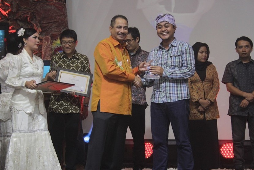 Menteri Pariwisata Arief Yahya (kiri) memberikan penghargaan Anugerah Pesona Bahari 2015 kepada salah seorang pemenang, Erwin Gumilar jurnalis majalah Venue