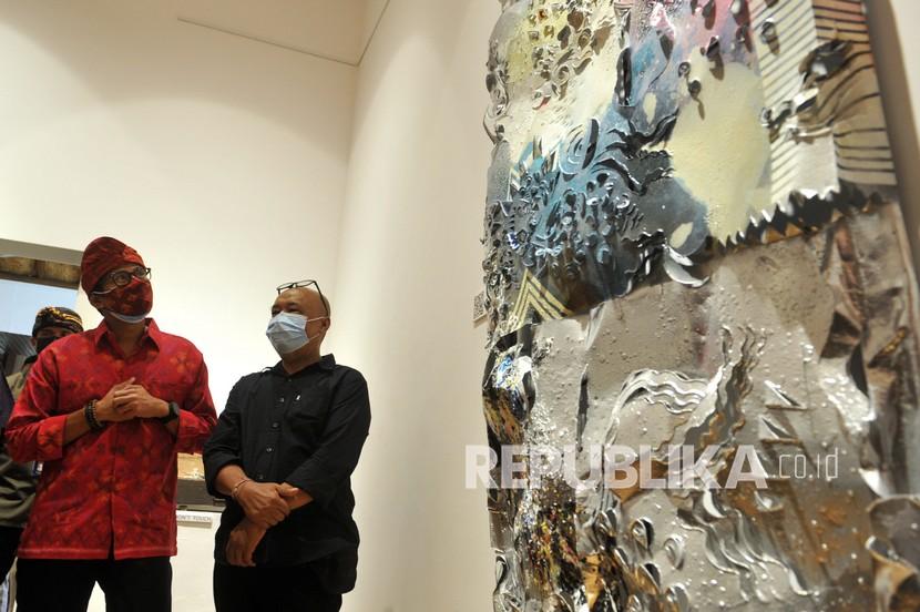 Menteri Pariwisata dan Ekonomi Kreatif (Menparekraf) Sandiaga Salahuddin Uno (kiri) mengamati karya yang dipamerkan dalam pameran seni rupa bertajuk Sipp Setiap Saat di Sanur, Denpasar, Bali, Senin (28/12/2020). Pameran tersebut menampilkan puluhan karya berbagai jenis seperti lukisan, instalasi dan patung sebagai wujud semangat para seniman yang tetap berkarya selama pandemi COVID-19. 
