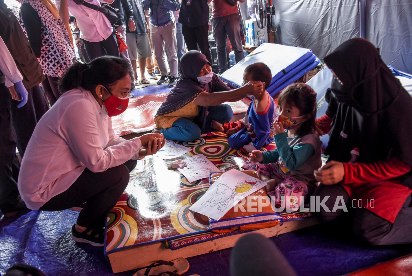 Menteri Pemberdayaan Perempuan dan Perlindungan Anak (PPPA) Bintang Puspayoga berbincang dengan warga yang mengungsi akibat tanah longsor saat kunjungan kerja di posko pengungsian di Lapangan Taman Burung Perum SBG, Parakan Muncang, Kecamatan Cimanggung, Kabupaten Sumedang, Jumat (22/1). Dalam kunjungan tersebut, Menteri PPPA Bintang Puspayoga memberikan bantuan berupa sembako dan perlengkapan alat sekolah kepada pengungsi korban bencana longsor dan memberi dukungan sosial serta hiburan kepada anak-anak.