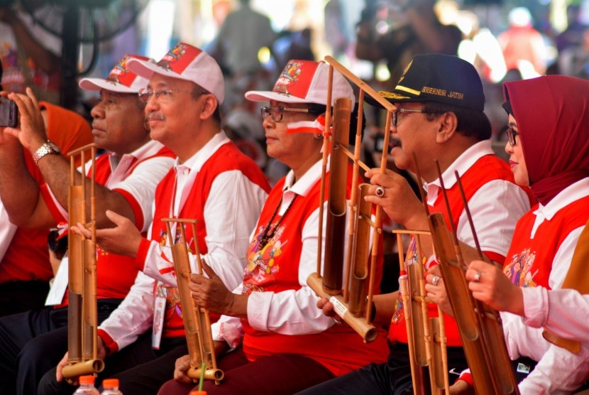 Menteri Pemberdayaan Perempuan dan Perlindungan Anak Yohana Susana Yembise (tengah) Gubernur Jawa Timur Soekarwo (kedua kanan) memainkan alat musik angklung saat puncak peringatan Hari Anak Nasional 2018 di Kebun Raya Purwodadi, Pasuruan, Jawa Timur, Senin (23/7).