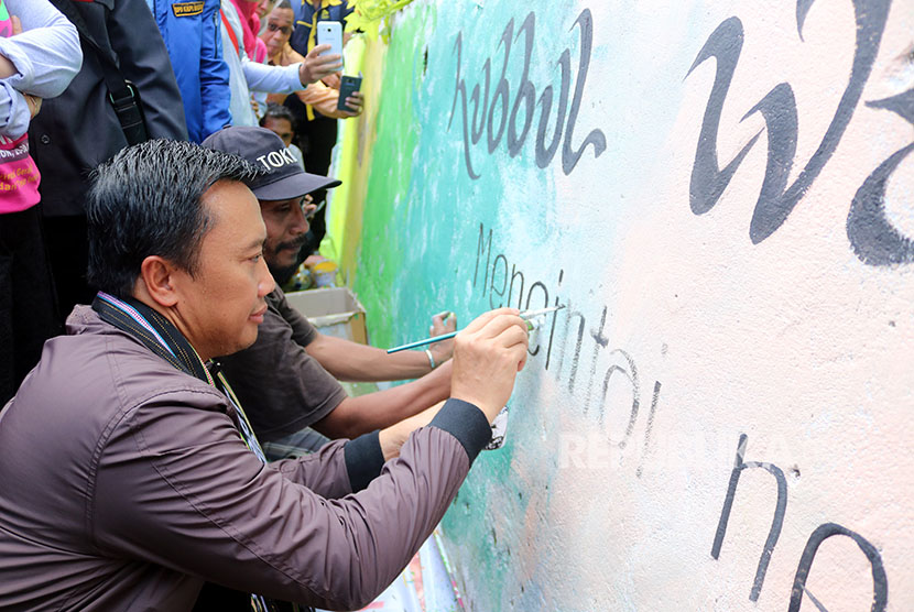 Menteri Pemuda dan Olahraga Imam Nahrawi (kanan) turut membuat mural saat bhakti sosial yang digelar Pengurus Pusat Fatayat Nahdlatul Ulama (NU) di Desa Batu Merah, Ambon, Maluku, Jumat (27/4). 