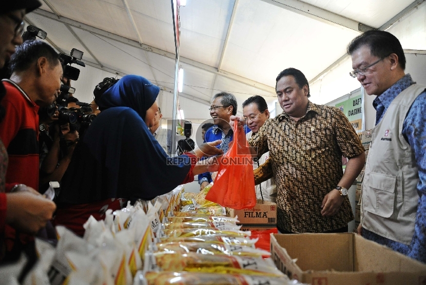 Menteri Perdagangan Rachmat Gobel (kedua kanan) melayani pembeli saat digelar Pasar Murah di halaman kantor Kemendag, Jakarta, Kamis (25/6). Republika/Tahta Aidilla