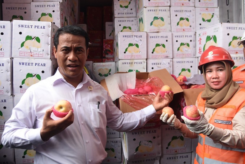 Menteri Pertanian Andi Amran Sulaiman (kiri) menunjukkan buah apel impor yang berada dalam Kontainer di Terminal Peti Kemas Surabaya, Jawa Timur, Jumat (4/3).