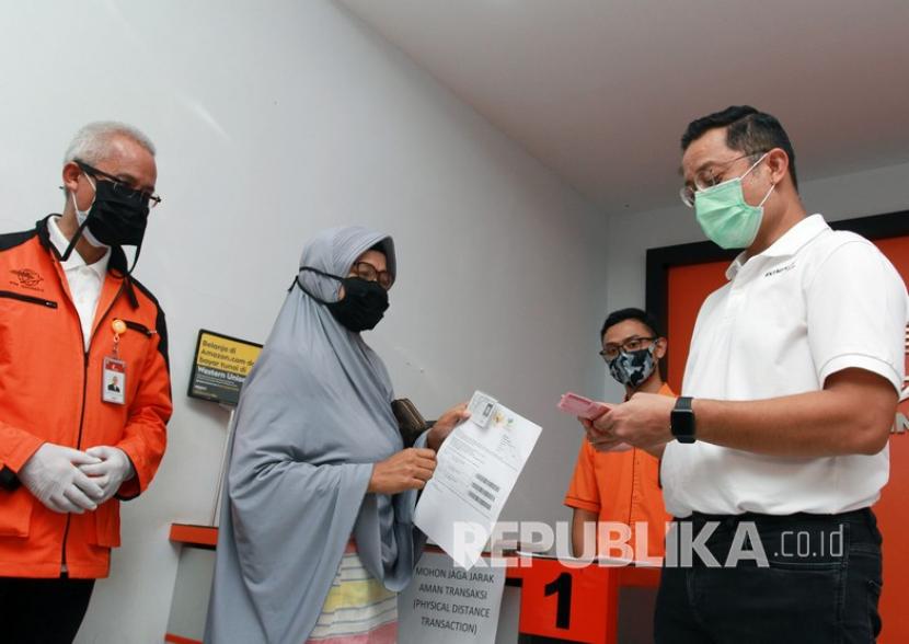 Menteri Sosial Juliari P Batubara (kanan) memberikan uang bantuan pemerintah kepada warga saat meninjau pencairan bantuan sosial tunai (BST) di Curug, Tangerang, Banten. (ilustrasi)