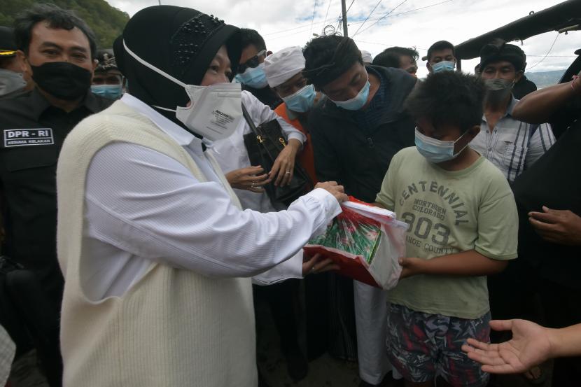 Menteri Sosial Tri Rismaharini (kiri) memberikan bantuan kepada warga yang terdampak gempa bumi di Desa Trunyan, Bangli, Bali, Senin (18/10/2021). Kunjungan Menteri Sosial di lokasi gempa bumi yakni Desa Trunyan, Kabupaten Bangli dan Desa Ban, Kabupaten Karangasem tersebut untuk meninjau dan menyerahkan bantuan sosial kepada korban dan warga yang terdampak bencana alam gempa bumi dengan magnitudo 4,8 SR yang terjadi pada Sabtu (16/10/2021).