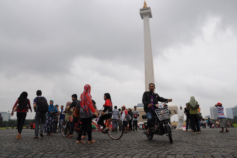   Meski hujan, banyak warga yang mengisi waktu libur dengan berwisata ke kawasan Monumen Nasional (Monas), Jakarta, Kamis (19/2).  (foto : MgROL_34)