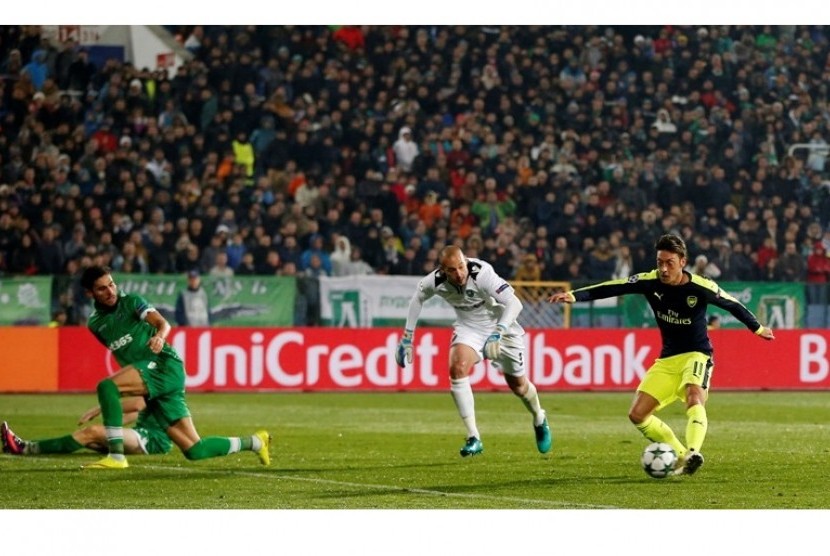 Mesut Oezil (kanan) saat mengecoh kiper dan dua pemain bertahan Ludogorets sebelum mencetak gol kemenangan Arsenal.