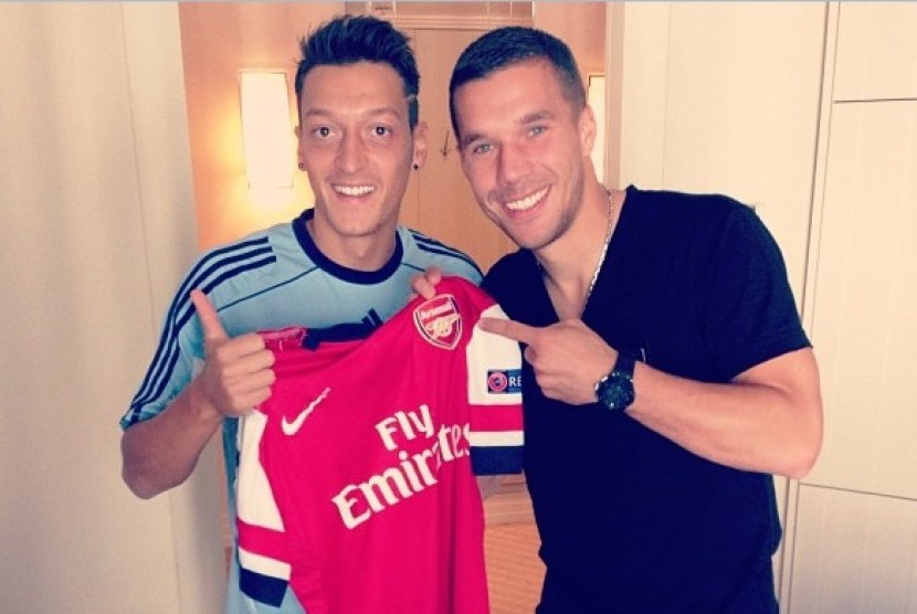 Mesut Oezil memegang jersey Arsenal bersama rekannya, Lukas Podolski