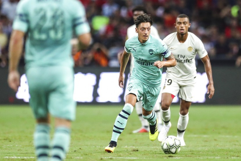 Mesut Oezil (tengah) menggiring bola saat membela Arsenal melawan PSG.