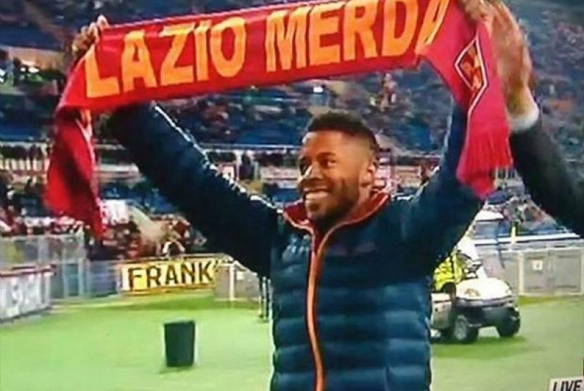 Michel Bastos menunjukkan syal yang bertuliskan hinaan terhadap Lazio saat diperkenalkan sebagai pemain baru AS Roma.