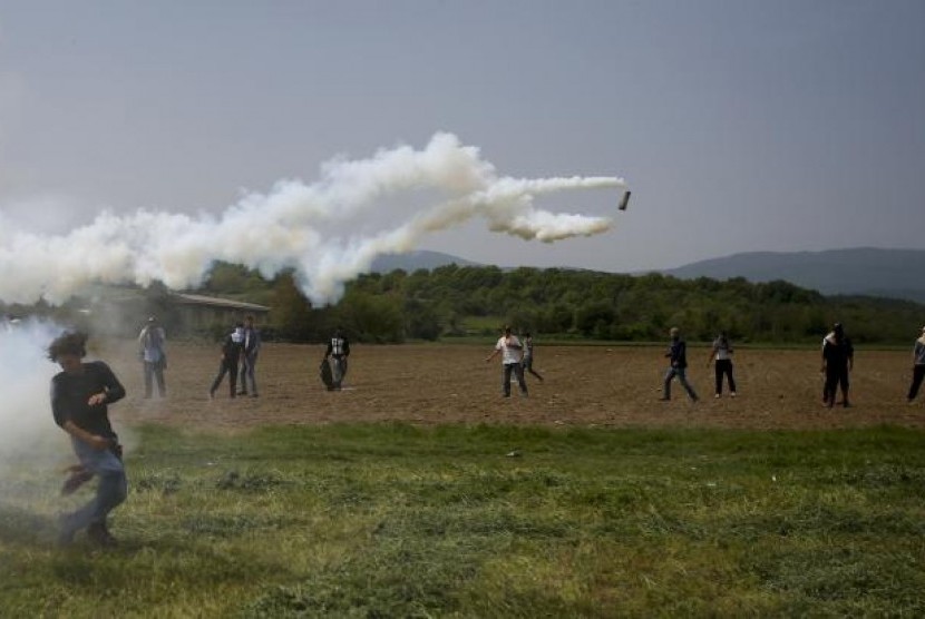 Migran melempar kembali gas air mata saat bentrok dengan polisi di kamp pengungsi di perbatasan Yunani-Makedonia dekat Desa Idomeni, Yunani, Jumat, 13 April 2016.