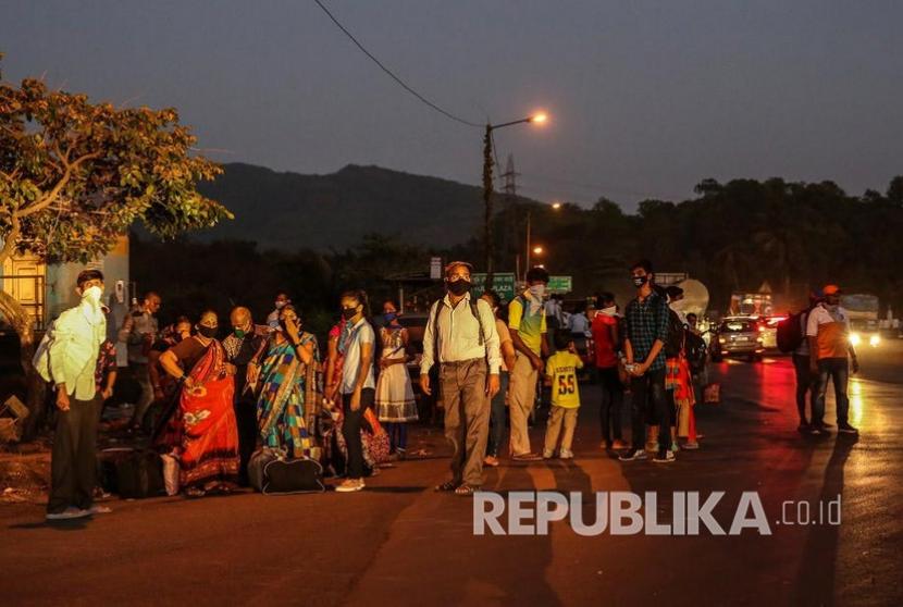 Pekerja migran menunggu transportasi untuk perjalanan pulang di jalan raya di pinggiran Mumbai, India, Selasa (12/5). Ribuan pekerja migran kembali ke desa mereka setelah pemerintah India mengumumkan masa perpanjangan lockdown selama dua minggu hingga 17 Mei. 