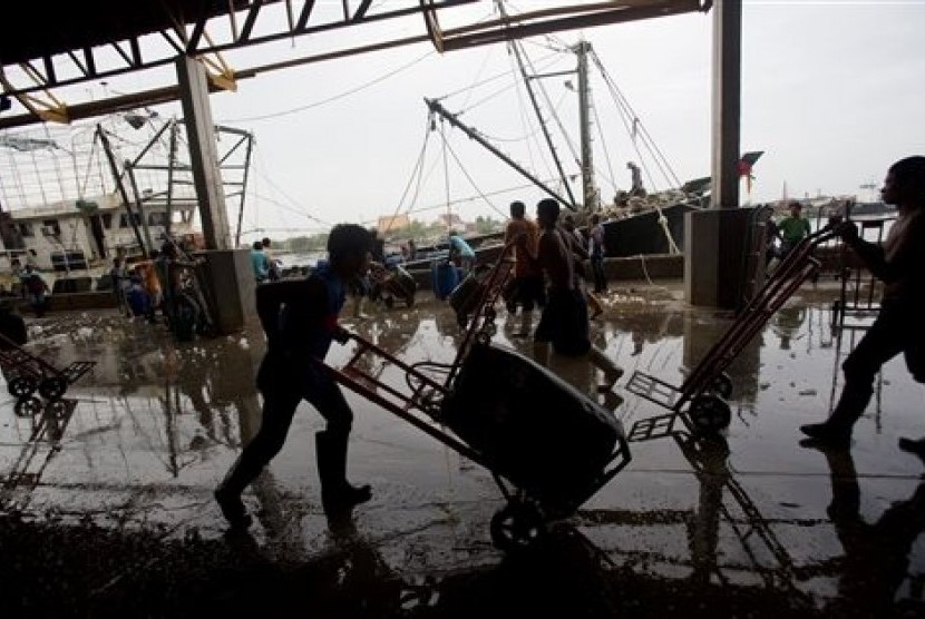 Migrant workers unload frozen fish from a boat at a fish market in west of Bangkok, Friday, June 20, 2014. The United States has blacklisted Thailand and Malaysia for failing to meet its minimum standards in fighting human trafficking.