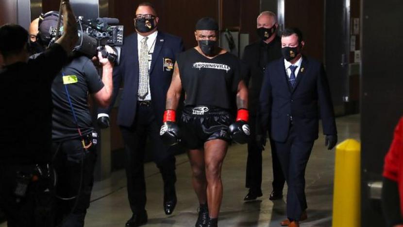 Mike Tyson mengenakan topi haji warna hitam saat memasuki ring.