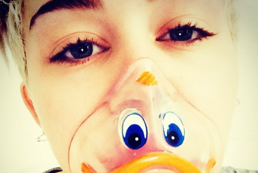 Miley Cyrus mengenakan masker oksigen berbentuk kepala Donald Bebek saat dirawat di rumah sakit.