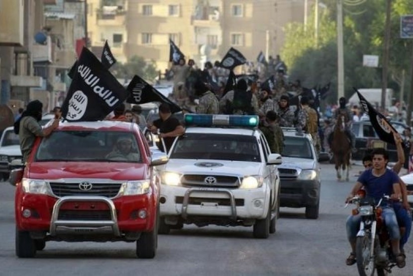 Militant Islamist fighters waving flags, travel in vehicles as they take part in a military parade along the streets of Syria's northern Raqqa province June 30, 2014.