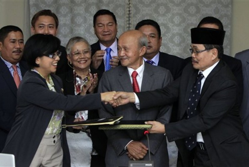Miriam Coronel-Ferrer chairperson of Philippine Government Peace Panel (front left) exchanges signed document with Mohagher Iqbal chief negotiator for the Moro National Liberation Front (front right), witnessed by Malaysian facilitator Abdul Ghafar Tengku 