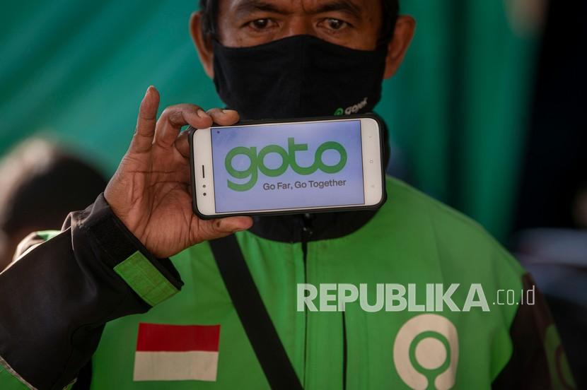 Mitra layanan ojek daring Gojek menunjukkan logo merger perusahaan Gojek dan Tokopedia yang beredar di media sosial di shelter penumpang Stasiun Kereta Api Sudirman, Jakarta, Jumat (28/5/2021). PT GoTo Gojek Tokopedia Tbk (GOTO) mencatatkan simpanan tunai atau kas setara Rp 29 triliun, yang dinilai cukup untuk meraih EBITDA Disesuaikan (Adjusted EBITDA) positif pada akhir 2023 serta mencapai kemandirian secara permodalan.