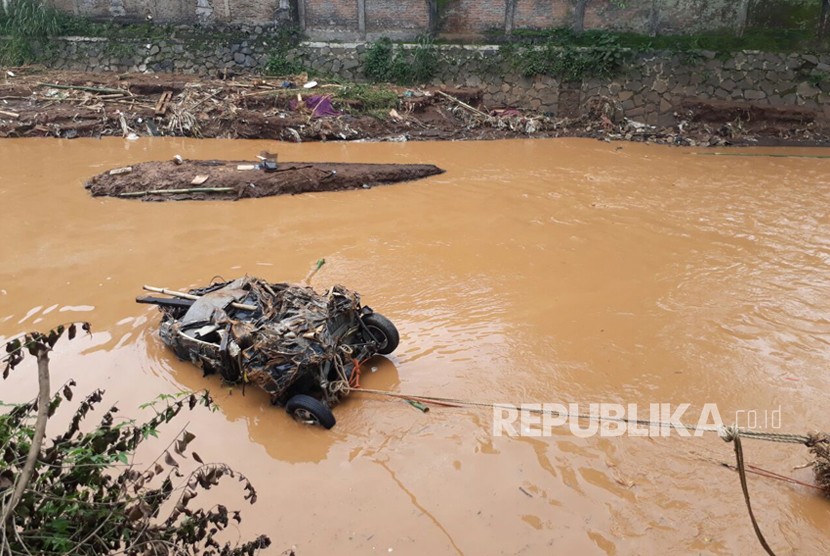 Mobil Daihatsu Xenia terbawa aliran sungai Cipamokolan saat banjir trrjadi di Kota Bandung, Selasa (20/3) kemarin. Petugas masih berusaha mengabgkat bangkai mobil.