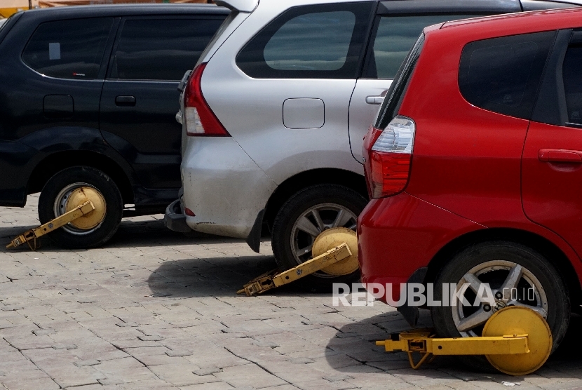  Mobil dengan gembok roda diparkir di Kawasan IRTI, Monas, Jakarta, Senin (3/4).